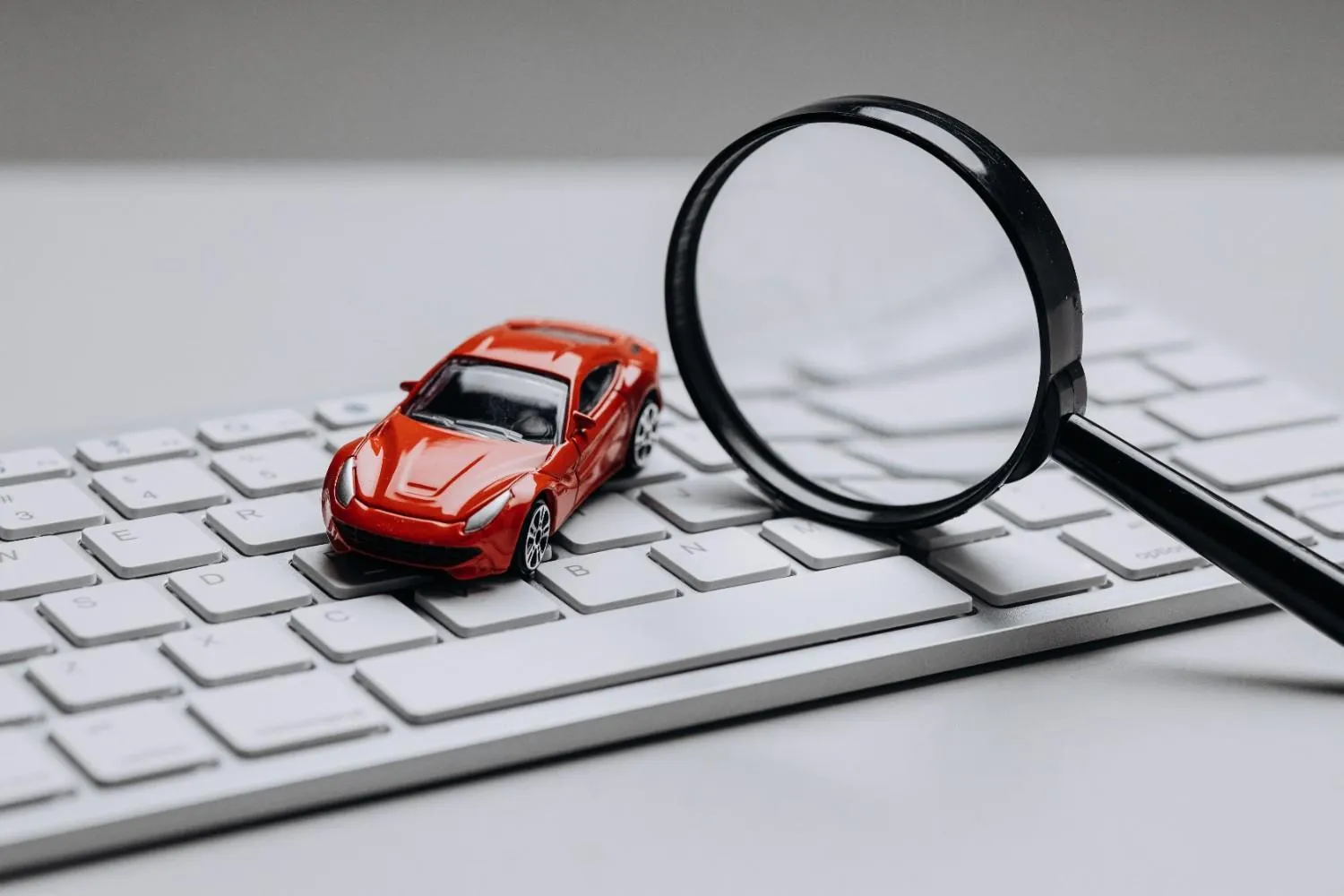 Toy car and a magnifying glass resting on a keyboard