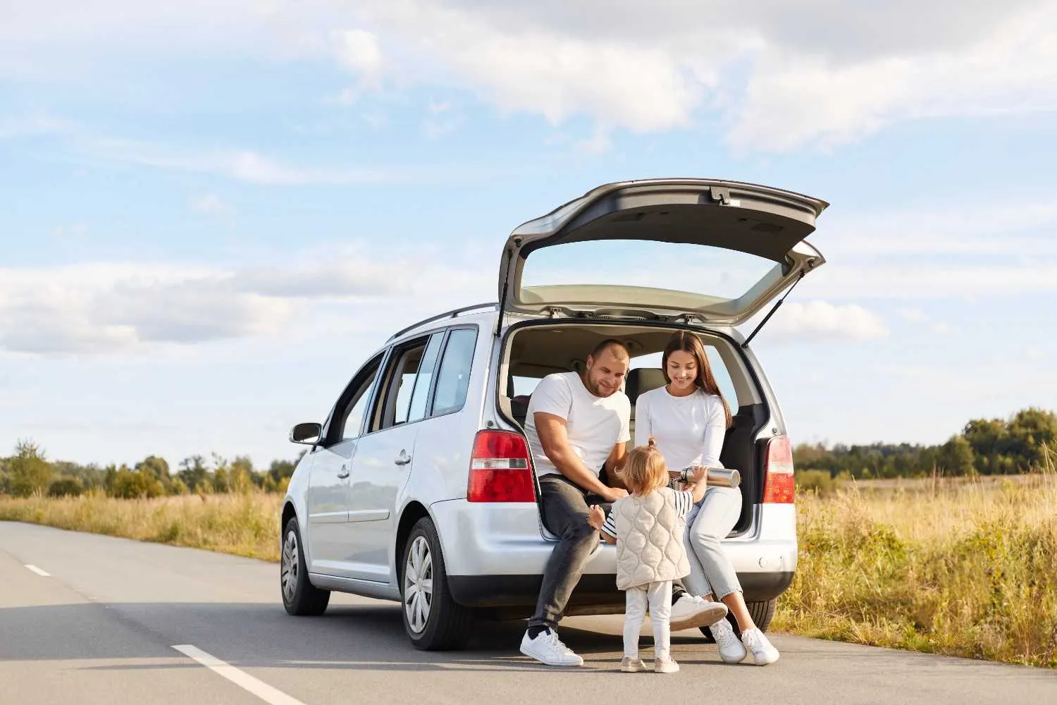 Family beside their car with the tailgate open on a country road