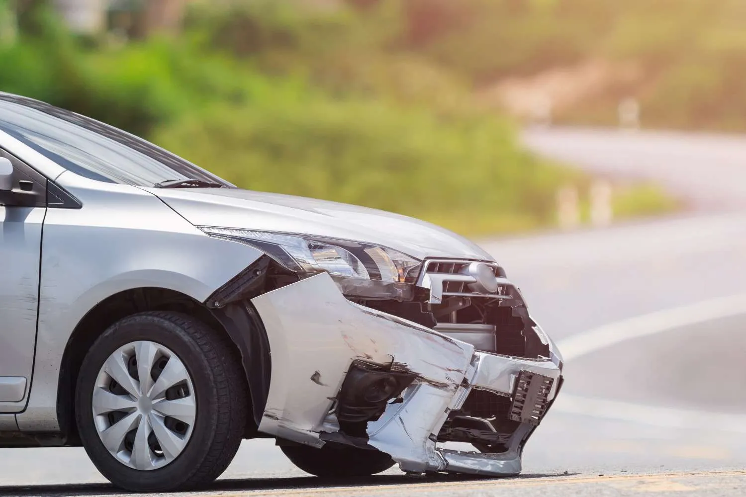 Silver car with a crumpled front bumper at the roadside